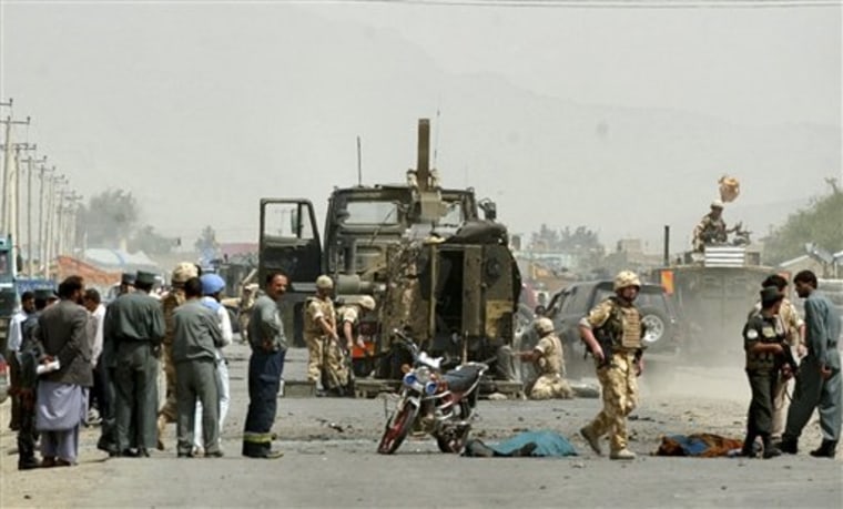 A British soldier from the International Security Assistance Force (ISAF) passes by dead bodies, covered, at the site of a suicide attack in Kabul, Afghanistan. 